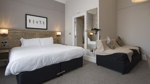 A hotel room with a large bed, a sofa, a mirror, and a framed artwork on the wall. - Owl, Hambleton by Marston's Inns (Selby)