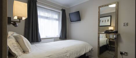 Une chambre d’hôtel avec un lit, un téléviseur fixé au mur, une table de chevet avec une télécommande et un grand miroir.