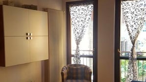 A room with a bed, a chair, a cabinet, and a window with curtains.