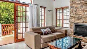 A living room with a sofa, a glass coffee table, and a fireplace. - St Francis Bay Luxury Lodge 2 (Saint Francis Bay)