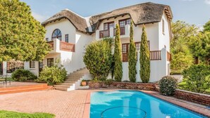 A two-story building with a swimming pool, surrounded by greenery and a brick pathway. - St Francis Bay Luxury Lodge 2 (Saint Francis Bay)