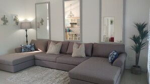 A modern living room with a sectional sofa, a fluffy rug, and three large mirrors. - Pepper Tree BnB (Sandton)