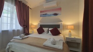 A neatly made bed with pillows and towels, a bedside lamp, and a painting on the wall. - Pepper Tree BnB (Sandton)