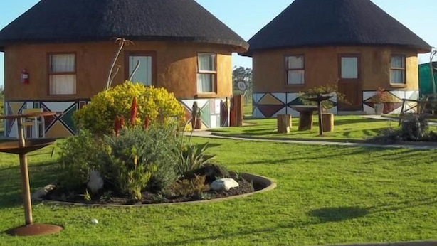 Two thatched-roof cottages with a small garden area in front. - African Sun Guest House (George)