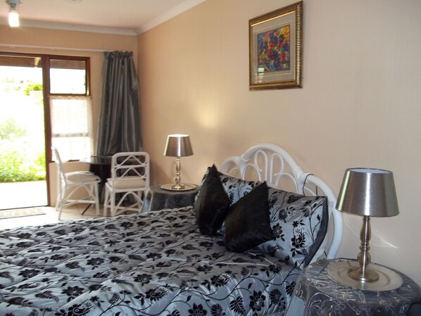 Une chambre à coucher avec un lit, deux oreillers, une table de chevet avec une lampe, une chaise et un tableau au mur.