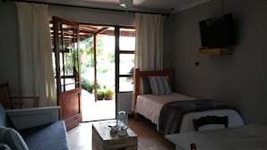 A room with a bed, a sofa, a table, and a TV. - African Sun Guest House (George)