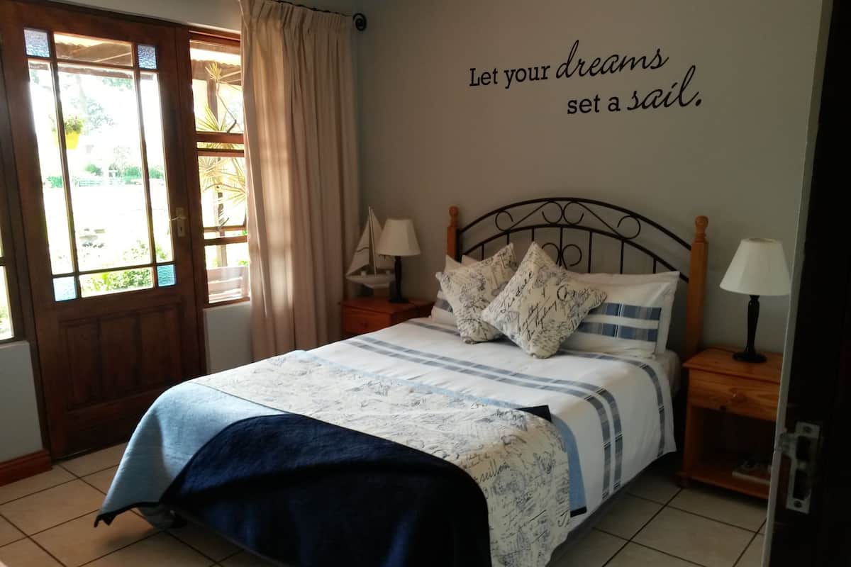 A bedroom with a bed, a wall with a motivational quote, a window, and a door.
