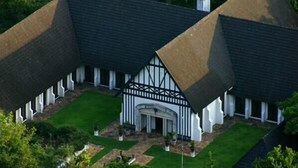 Un edificio ampio e bianco, con un tetto spiovente e una facciata simmetrica.