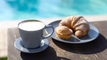 Una tazza di caffè e un croissant su un tavolo vicino a una piscina.