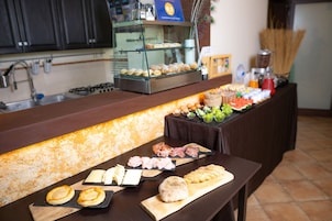 Un bufé de desayuno con diversos pasteles, carnes, quesos y frutas.