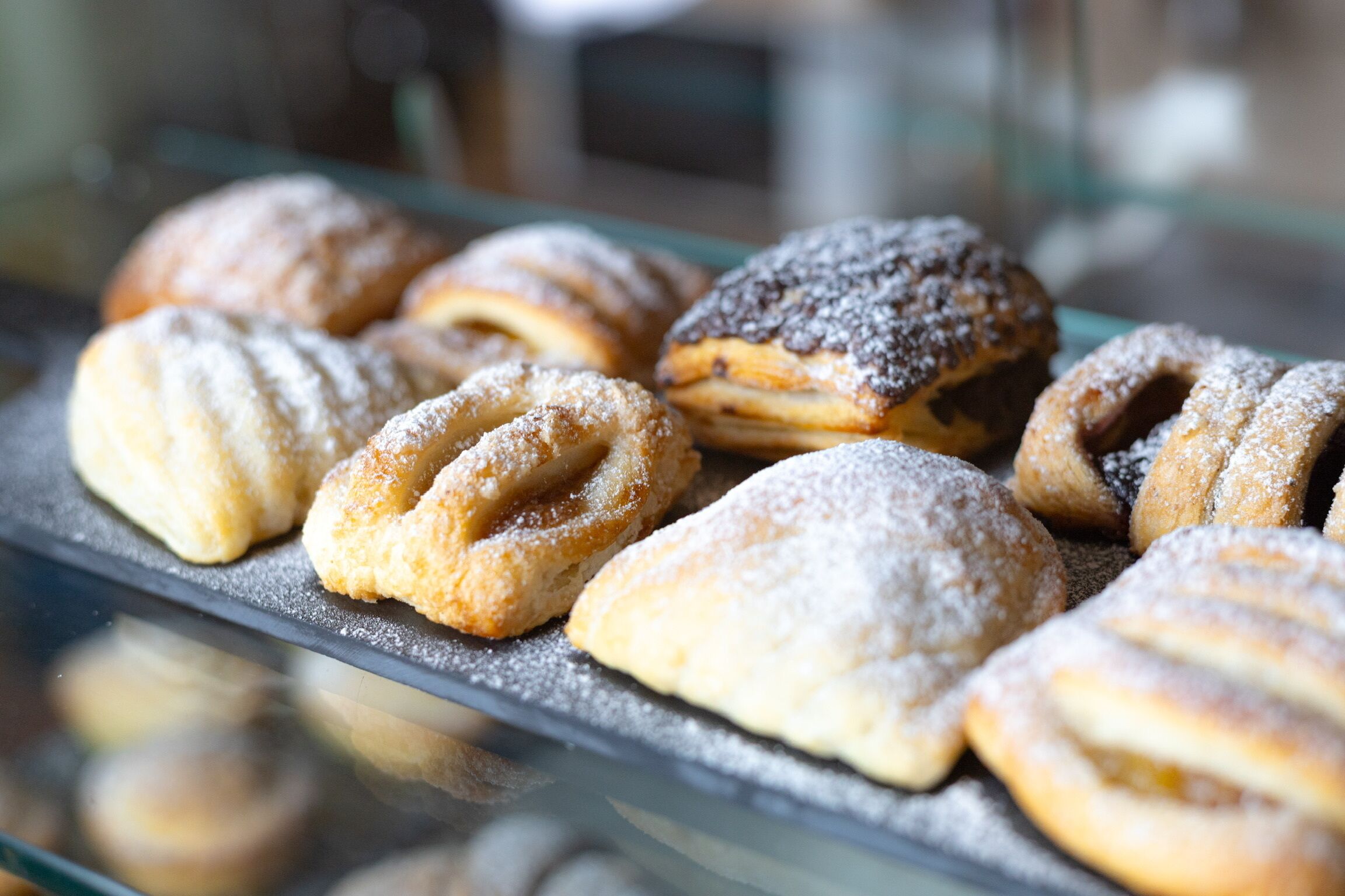 Una vetrina espositiva con diversi dolci, tra cui croissant e danesi, spolverati di zucchero a velo.