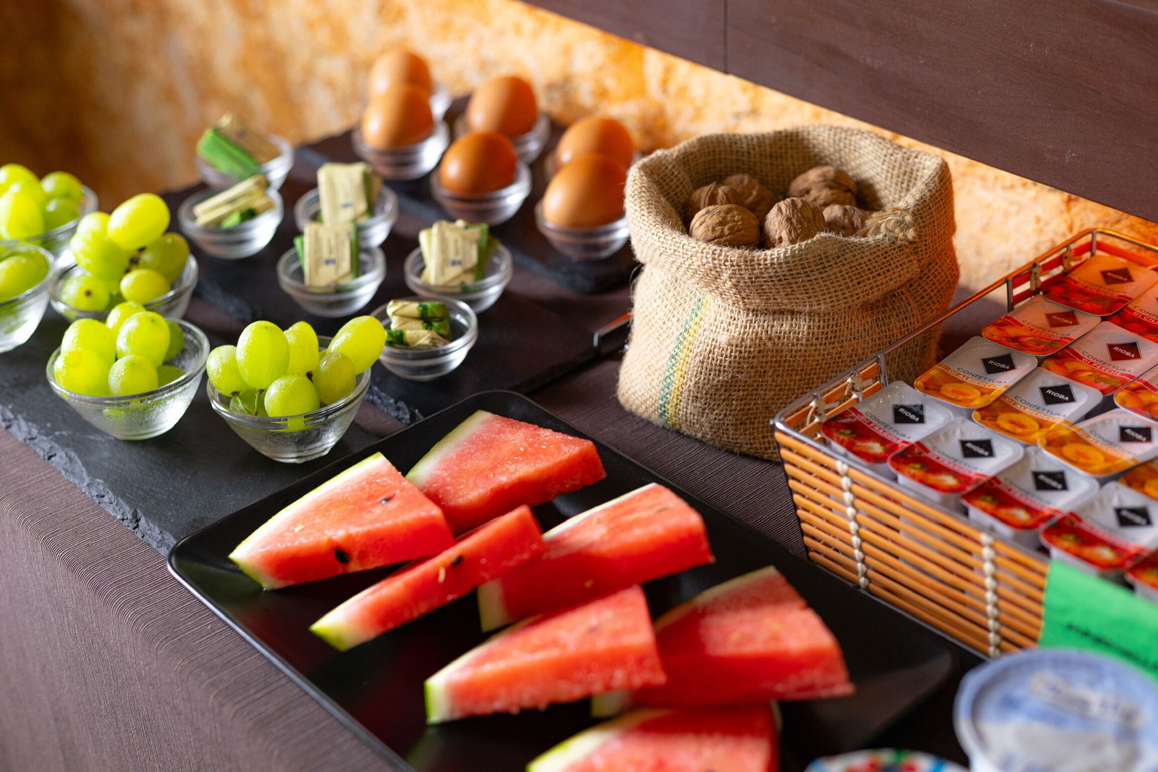 A table with various food items including watermelon slices, grapes, eggs, and nuts.