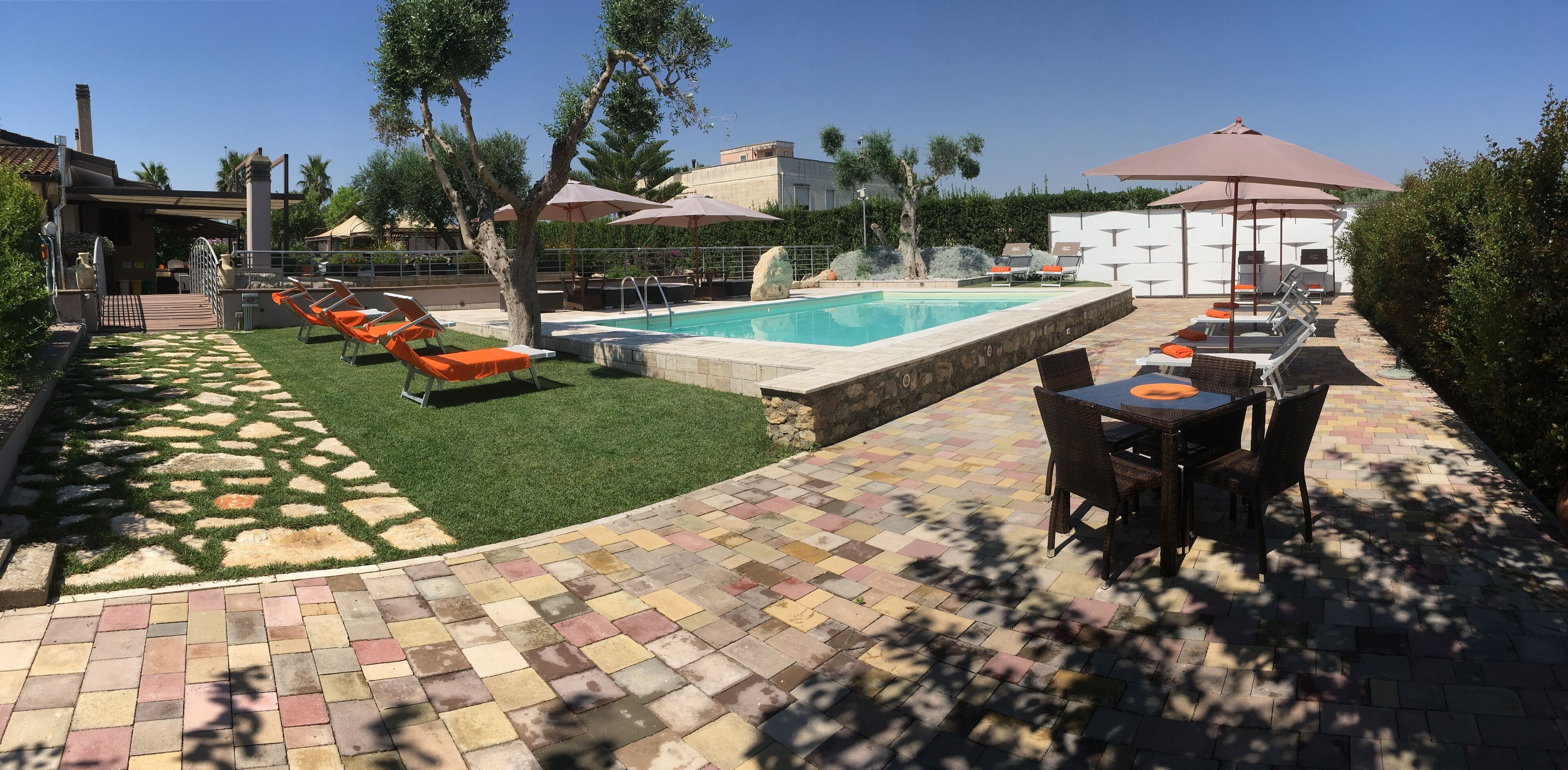 A pool area with lounge chairs, a table, and umbrellas.