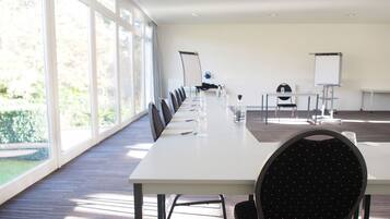 Een vergaderruimte met een lange tafel, stoelen, een whiteboard en een beamer.