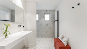A modern bathroom with a white sink, a large mirror, and a red bench. - Domein Martinus (Zoersel)
