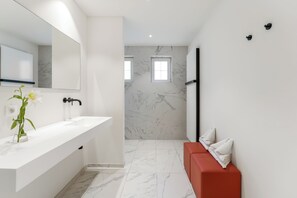A modern bathroom with a white sink, a large mirror, and a red bench. - Domein Martinus (Zoersel)