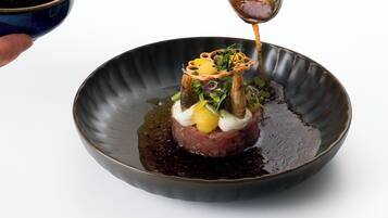 Une personne tenant une cuillère au-dessus d’un plat dans lequel on verse une sauce décorative.