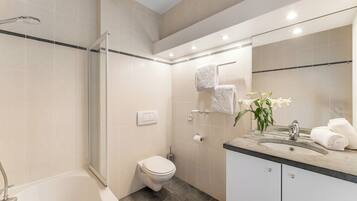 Une salle de bain moderne équipée d’une baignoire, de toilettes, d’une douche et d’un lavabo.