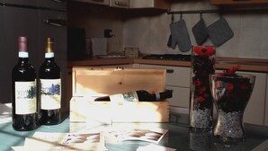 Eine Küchenarbeitsplatte mit Weinflaschen, einer Holzkiste und einer Blumenvase.