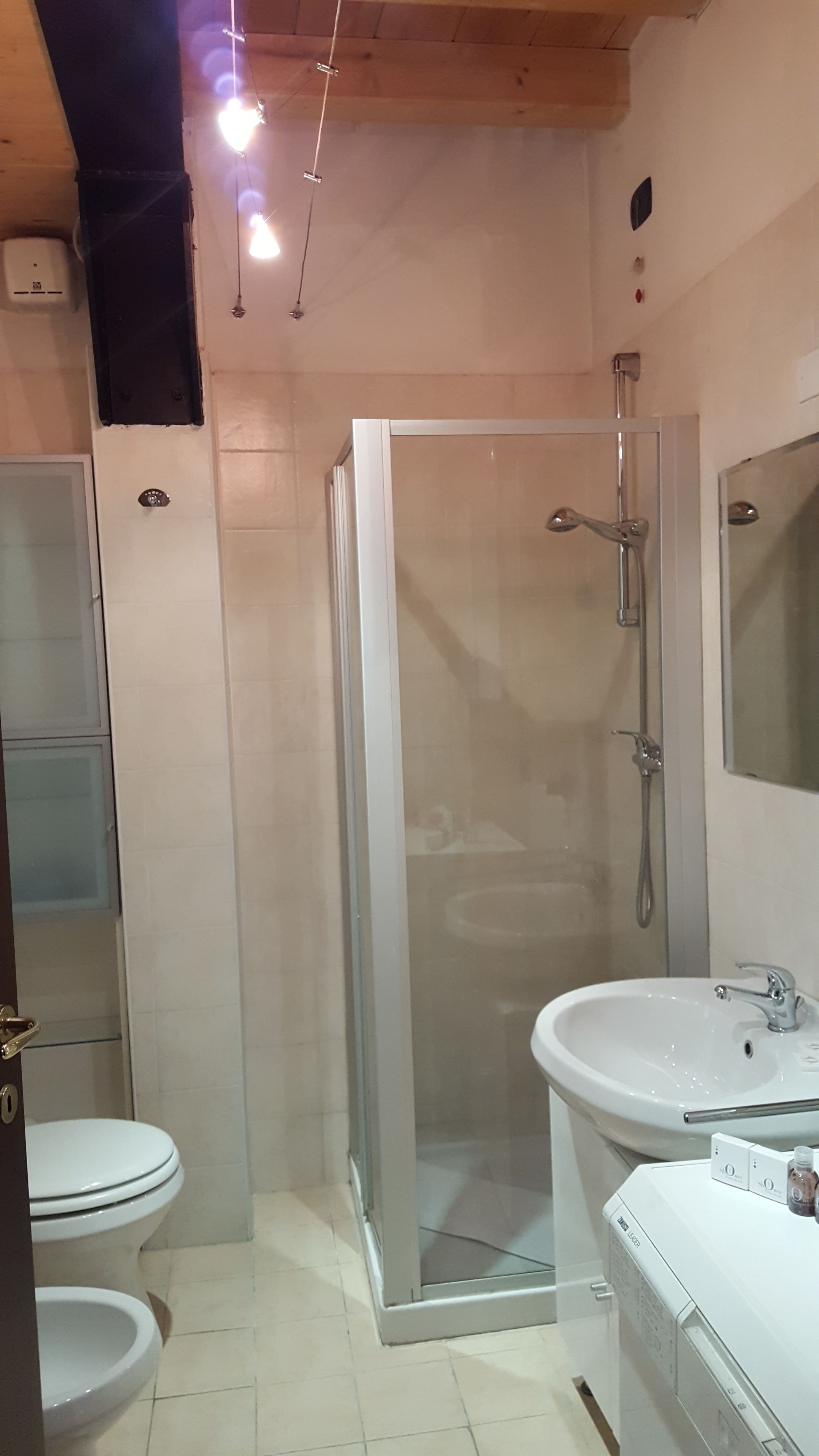 A modern bathroom with a glass-enclosed shower, a white sink, and a toilet.