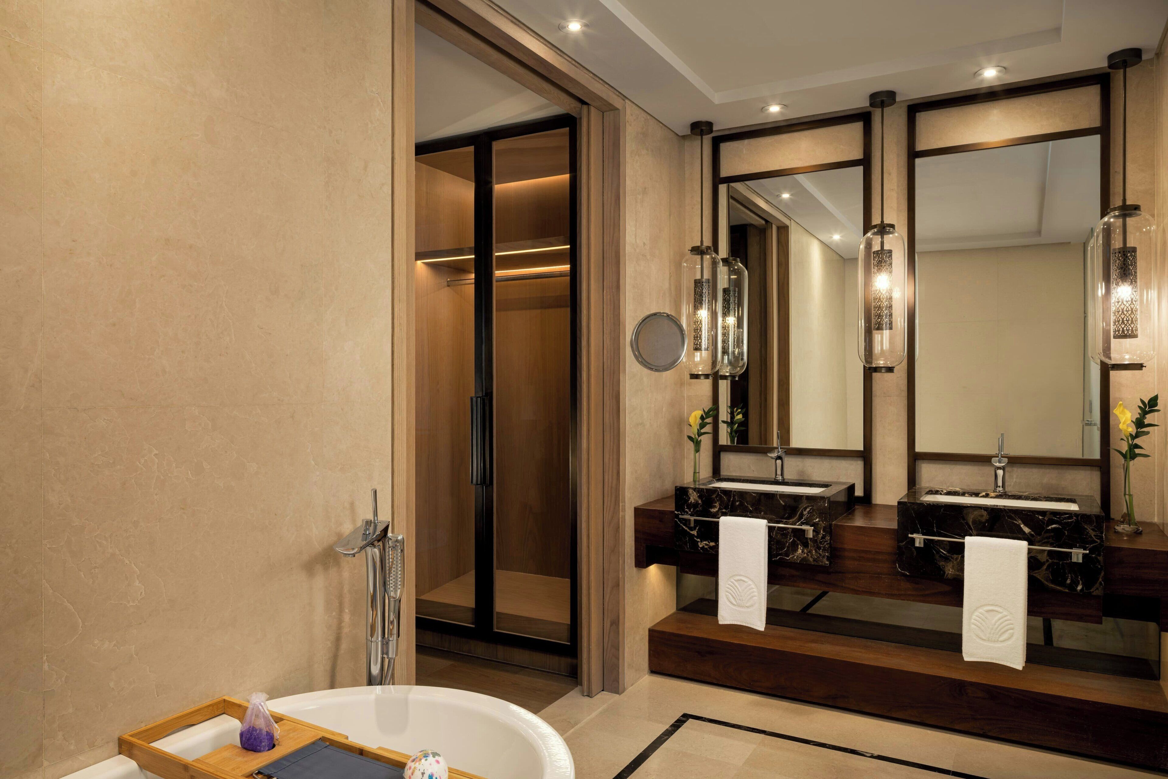 A modern bathroom with a walk-in shower, two sinks with marble countertops, and a large mirror.