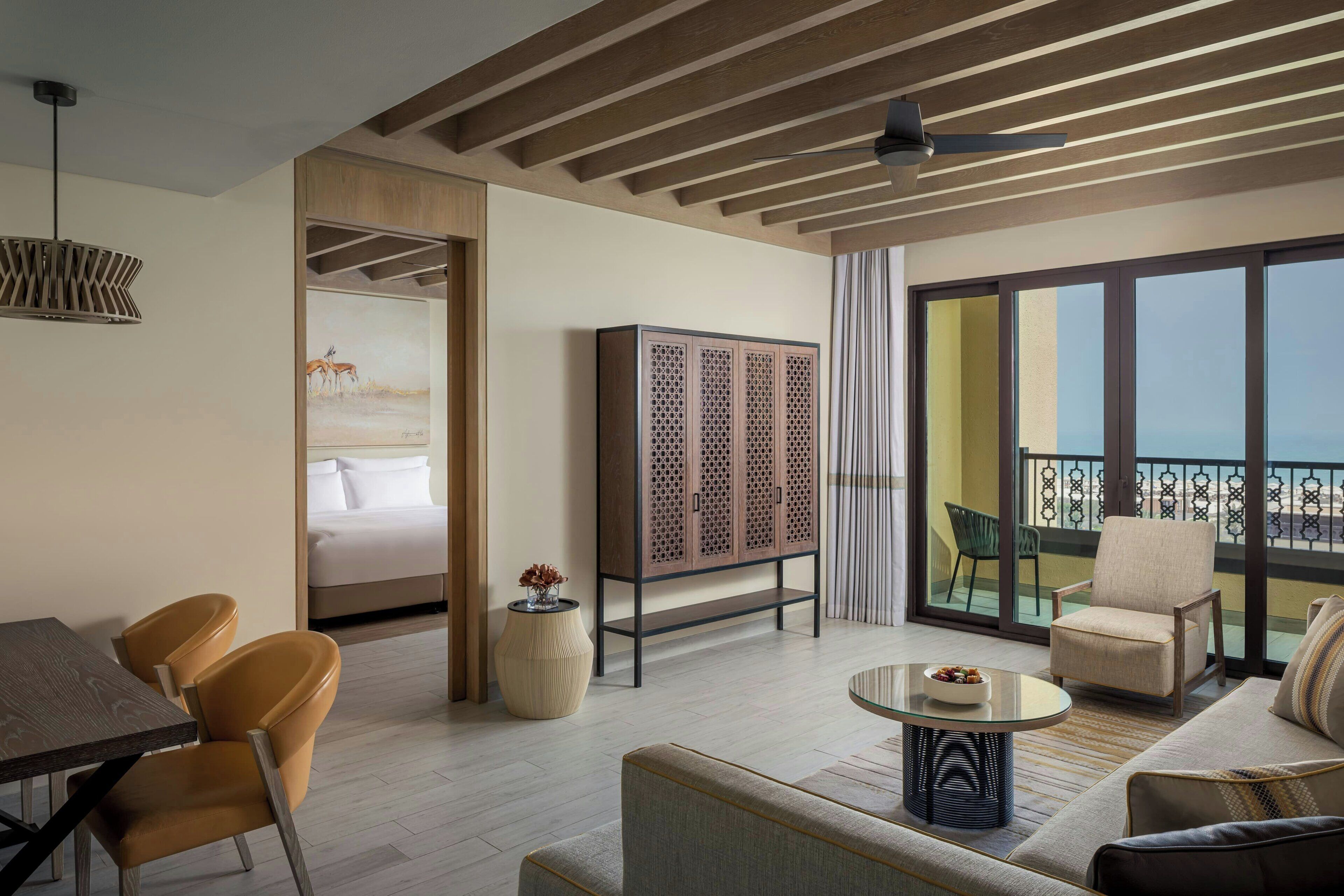 A modern hotel room with a balcony, a dining area, and a sofa.