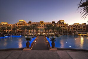 Relax by the rectangular pool surrounded by palm trees and a central fountain.