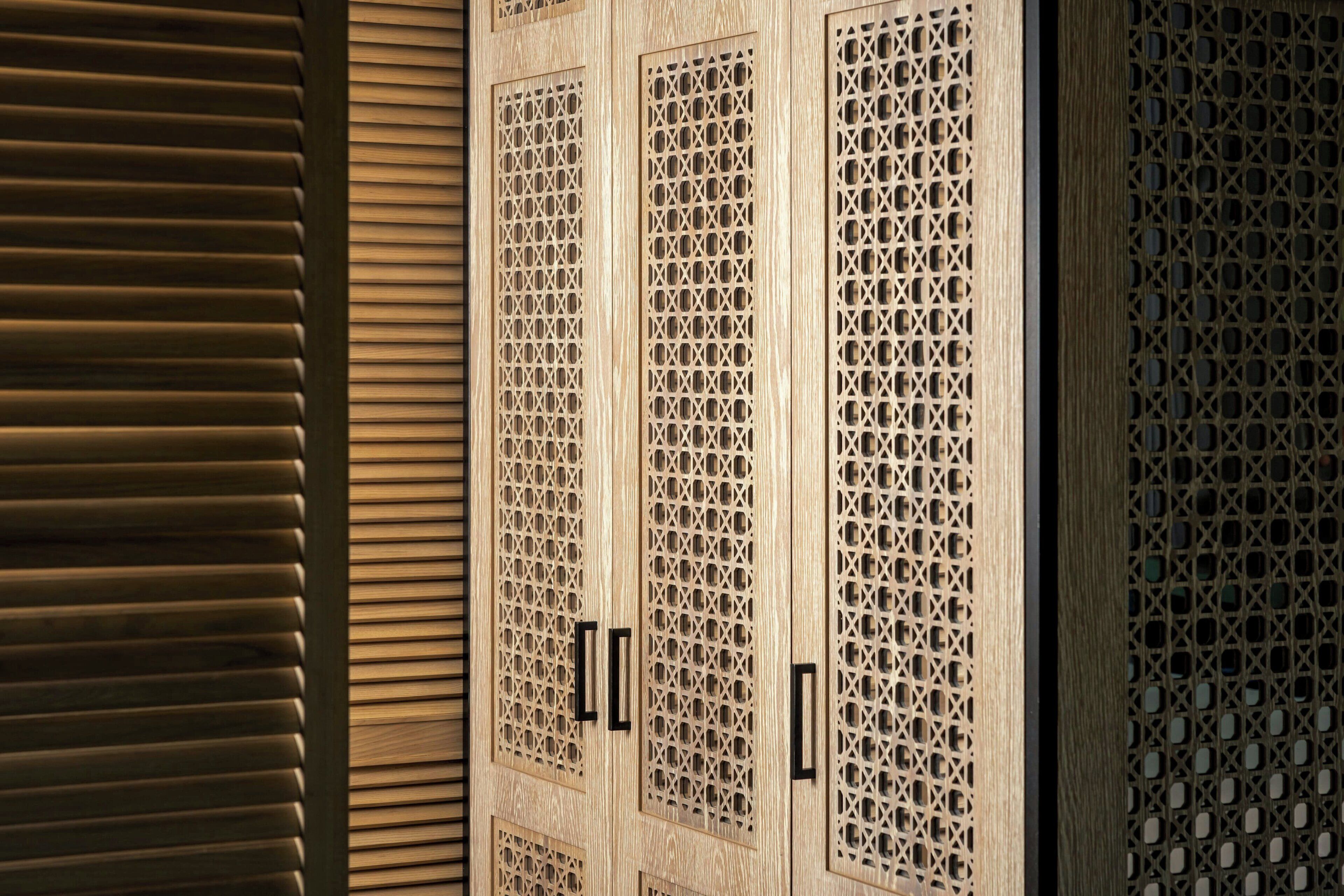 A wooden door with intricate lattice patterns and a sliding door to the left.