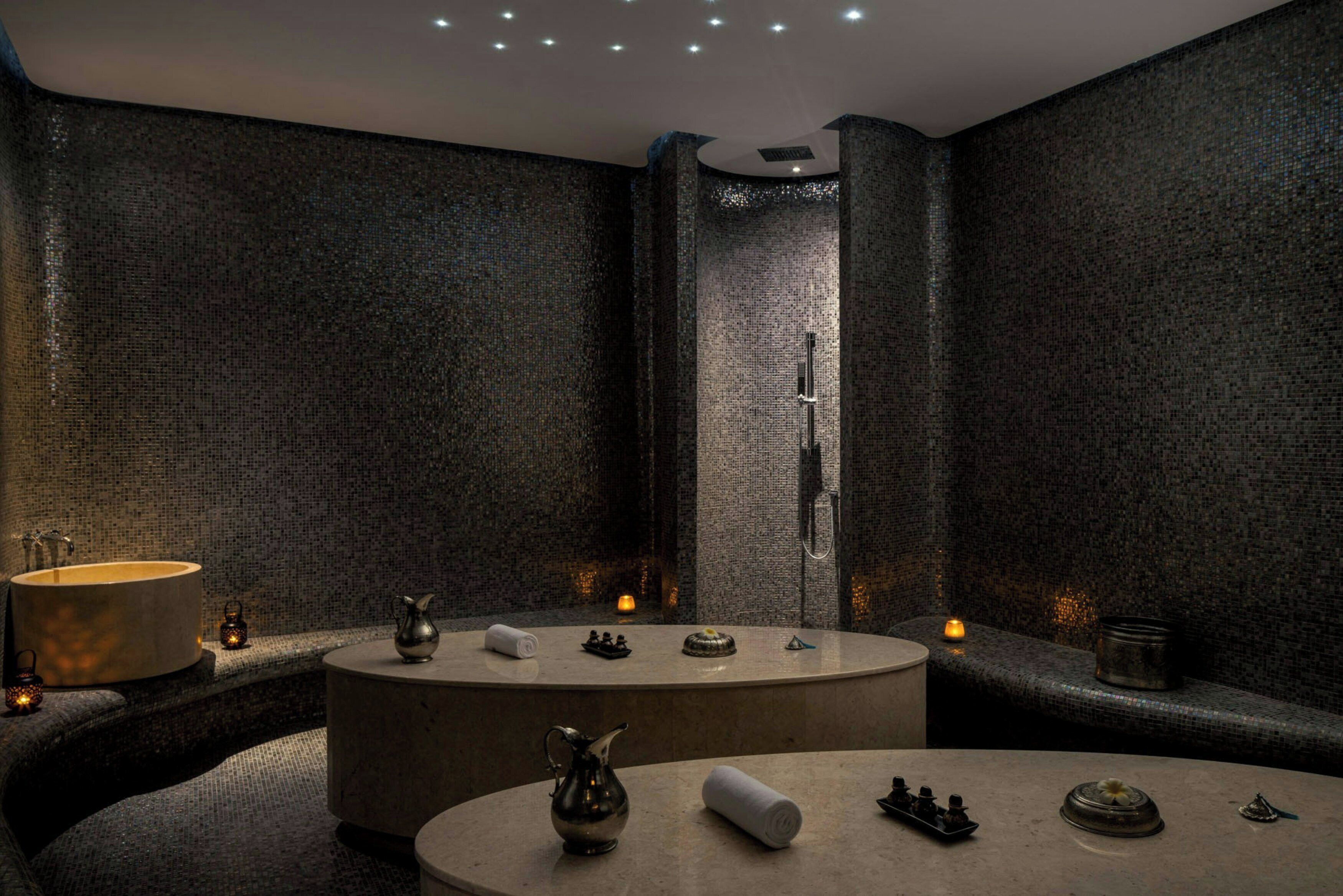 A modern bathroom with a large bathtub, a round sink, and a shower area.