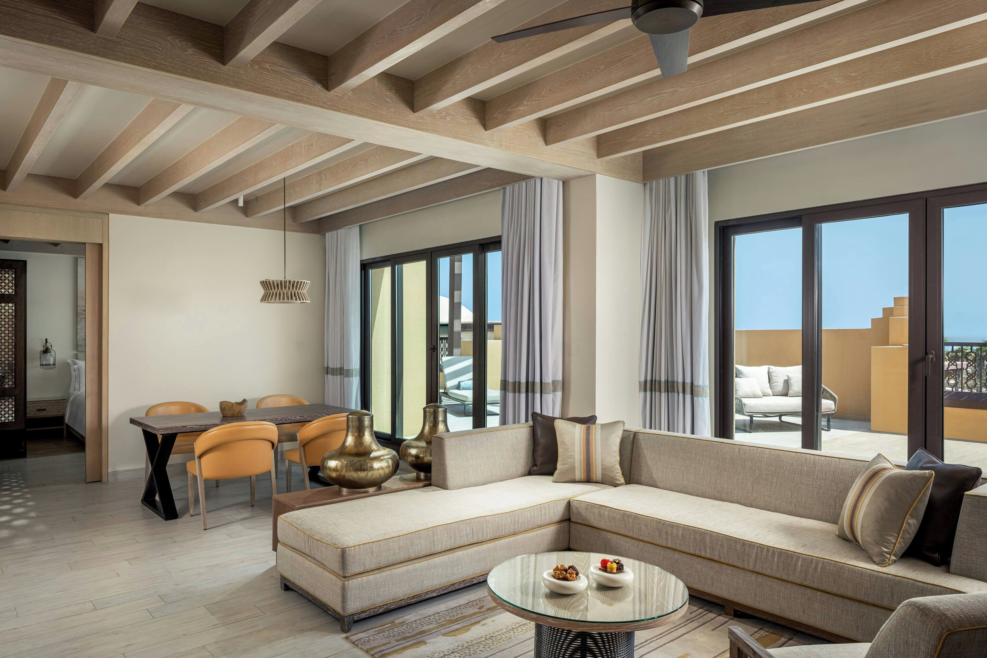 A modern living room with a sectional sofa, a dining table with chairs, and a glass coffee table.