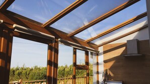 A kitchen with a large skylight, wooden beams, and a view of a fenced garden. - Hookless Holiday Homes (Templetown)
