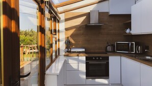 A modern kitchen with a skylight, wooden cabinets, and a view of the outdoors. - Hookless Holiday Homes (Templetown)