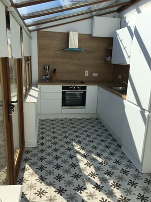 A compact kitchen with a built-in oven, a sink, and a wooden countertop. - Hookless Holiday Homes (Templetown)
