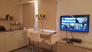 Une cuisine moderne avec des meubles blancs, un évier en acier inoxydable et un vase rempli de fleurs jaunes posé sur le plan de travail.