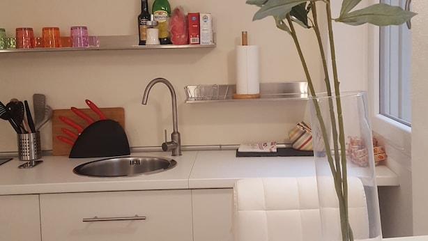Une cuisine moderne avec un évier, un plan de travail et un vase rempli de fleurs jaunes.