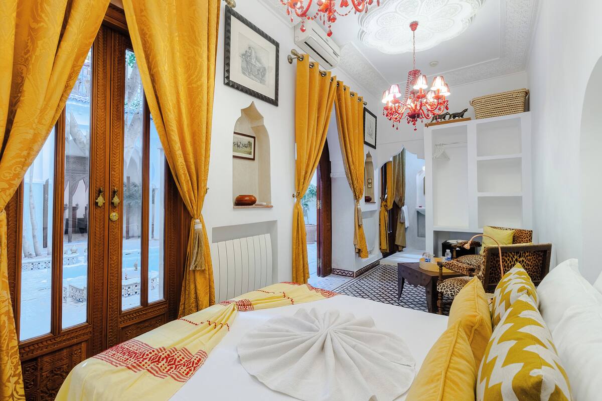 Une chambre d’hôtel avec un lit, une chaise, une table et un miroir.