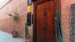 A wooden door with a number plate, two potted cacti, and a small plant on the ground. - Riad Asrari  (Marrakech)