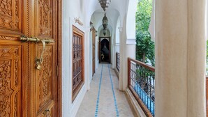 A corridor with ornate wooden doors, a patterned floor, and hanging lanterns. - Riad Asrari  (Marrakech)