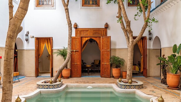 A courtyard with a pool, a wooden archway, potted plants, and a tiled floor. - Riad Asrari  (Marrakech)