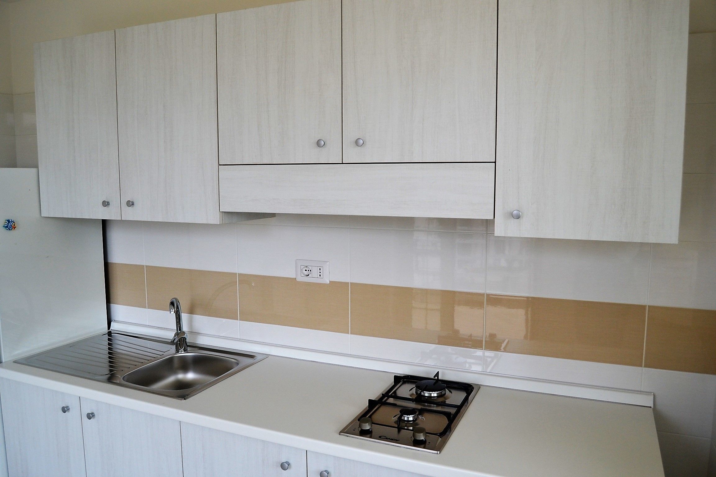 A kitchen with white cabinets, a stainless steel sink, and a gas stove.