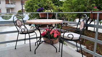 En udendørs terrasse med et rundt bord og fire stole, omgivet af et metalhegn.