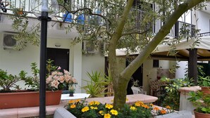 Un patio con un árbol, parterres y mobiliario exterior.