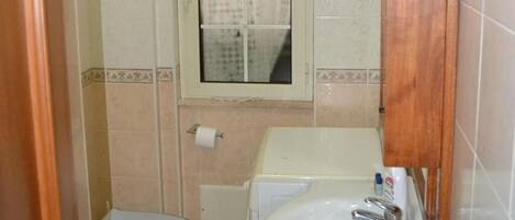 Un baño pequeño con inodoro, lavamanos y ventana.