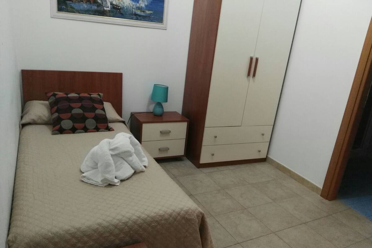 A bedroom with a bed, a nightstand, a wardrobe, and a painting on the wall.