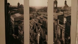 Ein sepiafarbenes Foto einer Stadtansicht mit historischen Gebäuden, darunter ein markanter Glockenturm und eine Kuppelstruktur.