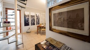 Eine moderne Treppe, ein Essbereich mit Tisch und Stühlen sowie eine Wand mit gerahmten Kunstwerken und einem großen Bild.