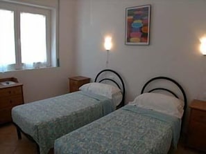 A bedroom with two single beds, a bedside table, a dresser, and a window. - Hotel Luana (Viareggio)