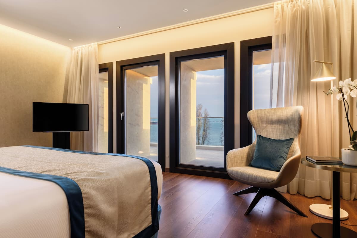 Een hotelkamer met een bed, een stoel, een televisie en uitzicht op de omgeving.