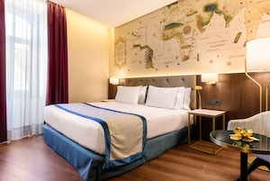 Une chambre d’hôtel avec un grand lit, une carte accrochée au mur, une petite table avec une lampe et une chaise.