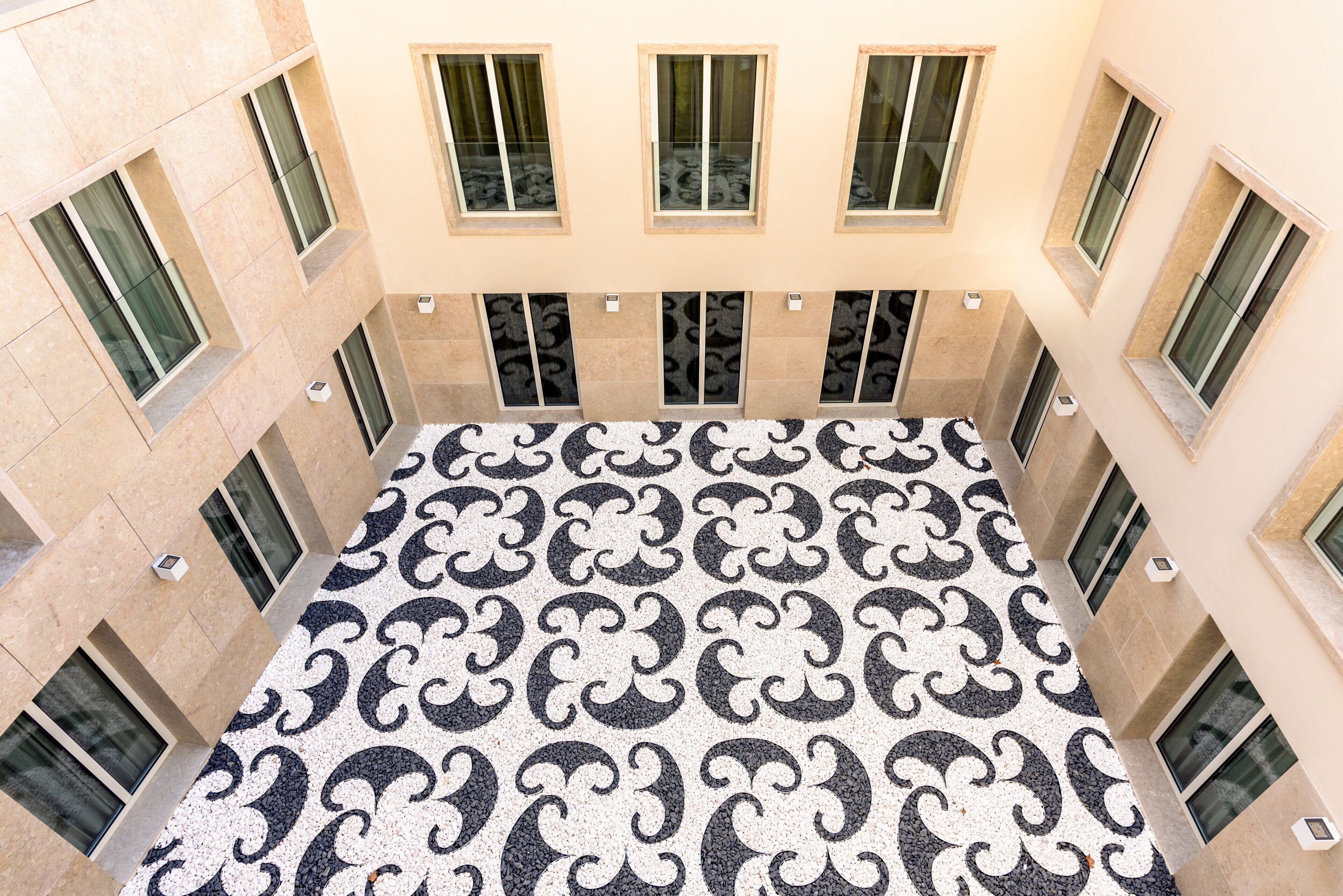 A high-ceiling atrium with a patterned floor, multiple windows, and a central open space.